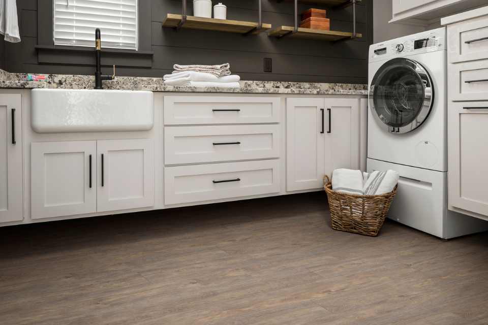 wood look luxury vinyl in modern laundry room with white cabinets and gray shiplap walls